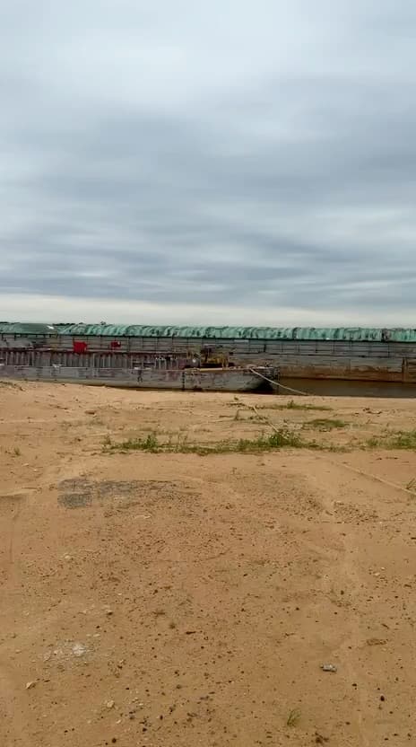 Convoy de barcazas con carga cubierta visto desde la playa del puerto
